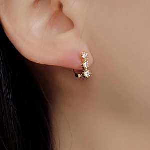 Close-up of gold 925 sterling silver stud earring featuring three vertical round zircons