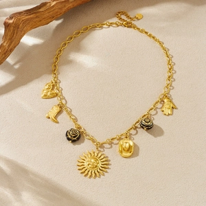 Vintage gold layered necklace with sun, heart and cowboy boot charms on desert sand texture