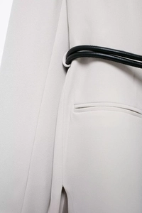 Detail of cream white blazer fabric texture with slim black leather belt and pocket
