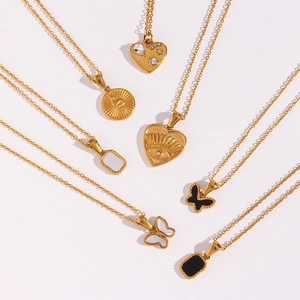 Detailed view of gold necklaces with heart, butterfly, and snake charms on white background