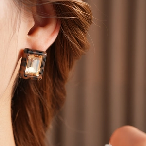 Close-up of square leopard resin earrings with amber crystal on female model's ear