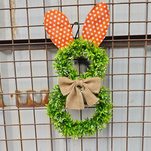 Easter bunny wreath with green leaves, orange polka dot ears and burlap bow for door