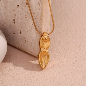 Détail du collier pendentif poignard plaqué or 18 carats sur fond de pierre texturé