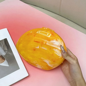 Detail view of yellow marble pattern acrylic clutch bag with glossy stone texture finish
