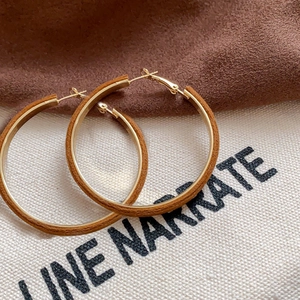 Close-up of brown flocked geometric hoop earrings with a metallic finish on fabric background