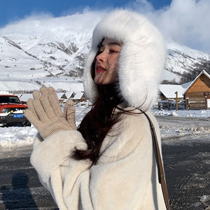 Winter faux fur earmuff hat with soft knit gloves and plush coat in a snowy landscape