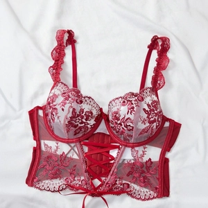 Detail of red floral lace bra with underwire support and adjustable front lacing