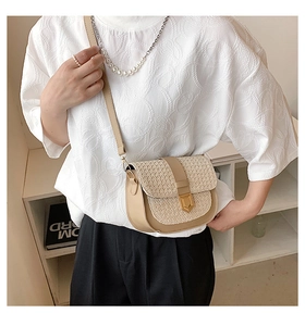 Detail view of woven straw and beige leather crossbody bag shown on model for daily styling
