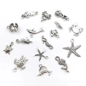 Flat lay of antique silver ocean charms featuring seahorse, starfish and sea turtle