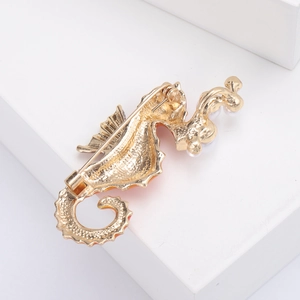 Detail view of the golden seahorse brooch back showing pin clasp and pearl accents