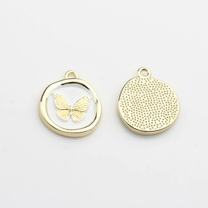 Detail of round golden butterfly charms with white enamel inlay and textured reverse side
