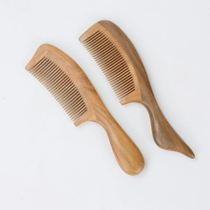 Natural green sandalwood hair comb with large ergonomic curved handle in studio lighting
