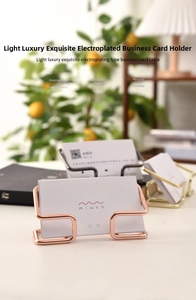 U-shaped gold metal business card holder on office desk with warm lighting