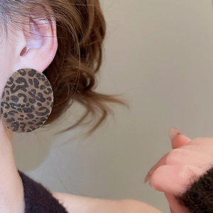 Close-up of model wearing large round leopard print earrings with a vintage flocked texture