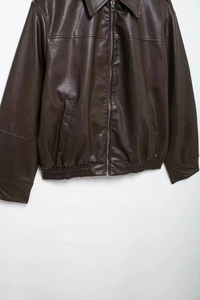 Detail of dark brown faux leather bomber jacket with metal zipper and ribbed hem