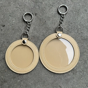 Detail van twee beige lederen badgehouders in de vorm van een kat met kettingen in twee maten