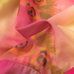 Dettaglio macro della sciarpa in chiffon con stampa floreale sfumata e bordi rifiniti