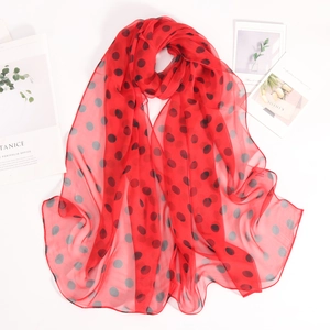 Dettaglio di una leggera sciarpa in chiffon rosso con eleganti pois neri e texture