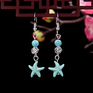 Close-up of Bohemian star fish earrings with turquoise beads and silver rose detail