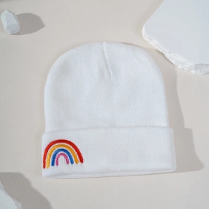 Detailed close-up of white knit beanie featuring colorful rainbow embroidery on the cuff
