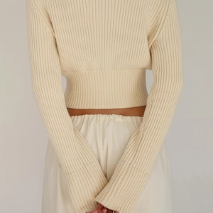Close-up of cream ribbed knit fabric texture and high-waisted slim fit design on a sweater