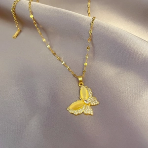 Macro view of gold butterfly pendant with yellow crystals on soft satin fabric