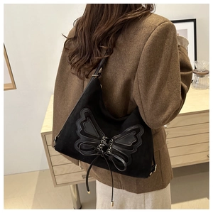Detail of black suede shoulder bag with leather bow decoration and ribbon strap