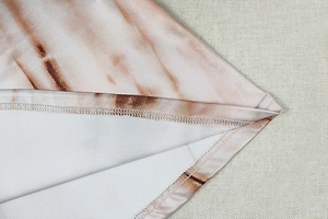 Close-up of the professional overlock stitching on a marble print V-neck long sleeve dress