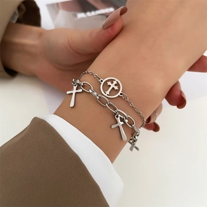 Detail of silver layered chain bracelet with cross pendants against a suit sleeve
