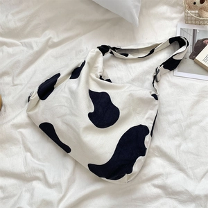 Detail of corduroy cow print tote bag with adjustable black strap buckle on white linen
