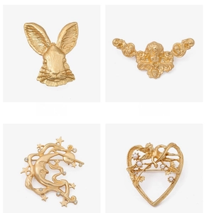 Detail view of vintage gold brooches featuring rabbit, cherub, moon and heart designs