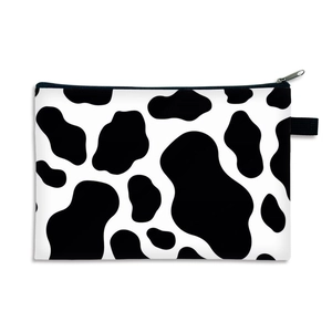 Portable cow print cosmetic bag with black zipper and handle on a white background