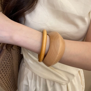 Détail de deux bracelets en bois naturel avec veinage unique sur le poignet d'une femme