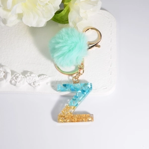 Detail of letter Z keychain with blue stones, gold foil, and mint green pompom