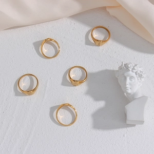 Flat lay of five vintage gold-tone seal rings with floral motifs on a white textured surface