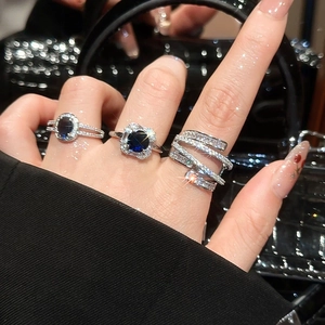 Three silver luxury rings with blue sapphire and zircon stones worn by a model