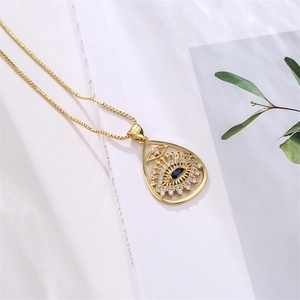 Macro della collana con ciondolo malocchio placcato oro e gemma blu su libro bianco