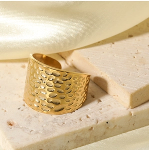 Close-up of golden hammered texture stainless steel adjustable ring on stone