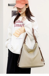 Grande borsa a tracolla minimalista in tela beige con spalline marroni indossata