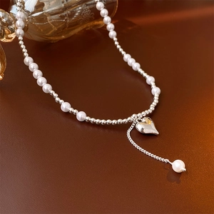 Silver heart pendant necklace with pearl beads displayed on a dark glossy surface