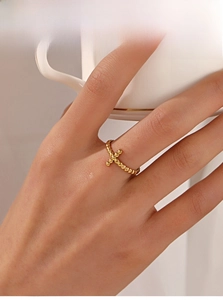 Detail of 18K gold plated beaded ring with a small cross design worn by a model