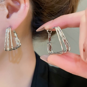 Detailed close-up of multi-layer geometric silver earrings in a stylish U-shape design