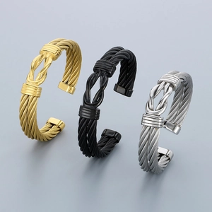 Three-color woven wire cable bracelets in gold, black, and silver with knot detail