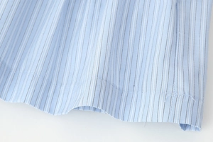 Detailed macro view of light blue striped cotton fabric showing hem stitching quality