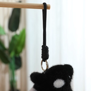 Close-up of plush animal keychain with black braided rope and silver metal ring