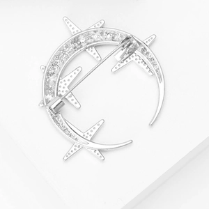 Macro shot of silver crescent moon and star brooch showing back pin and pave rhinestones