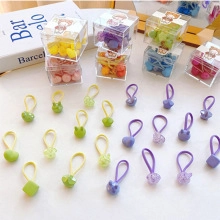 Close-up of colorful heart and star shaped hair ties in a transparent storage box