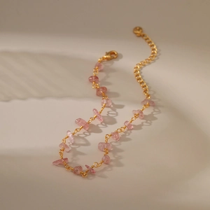 18K gold chain bracelet with irregular pink crystal stones on soft beige background