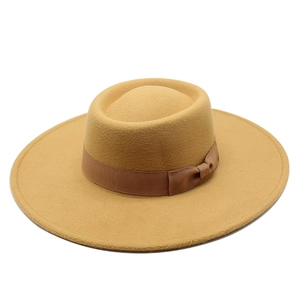 Camel wool fedora hat with wide brim and brown ribbon bow tie decoration on white background