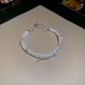 Detail of double-layer pearl bracelet with adjustable draw-string clasp and drop crystal